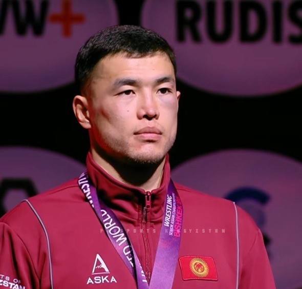 Wrestler on the podium with medal, red ceremony jacket